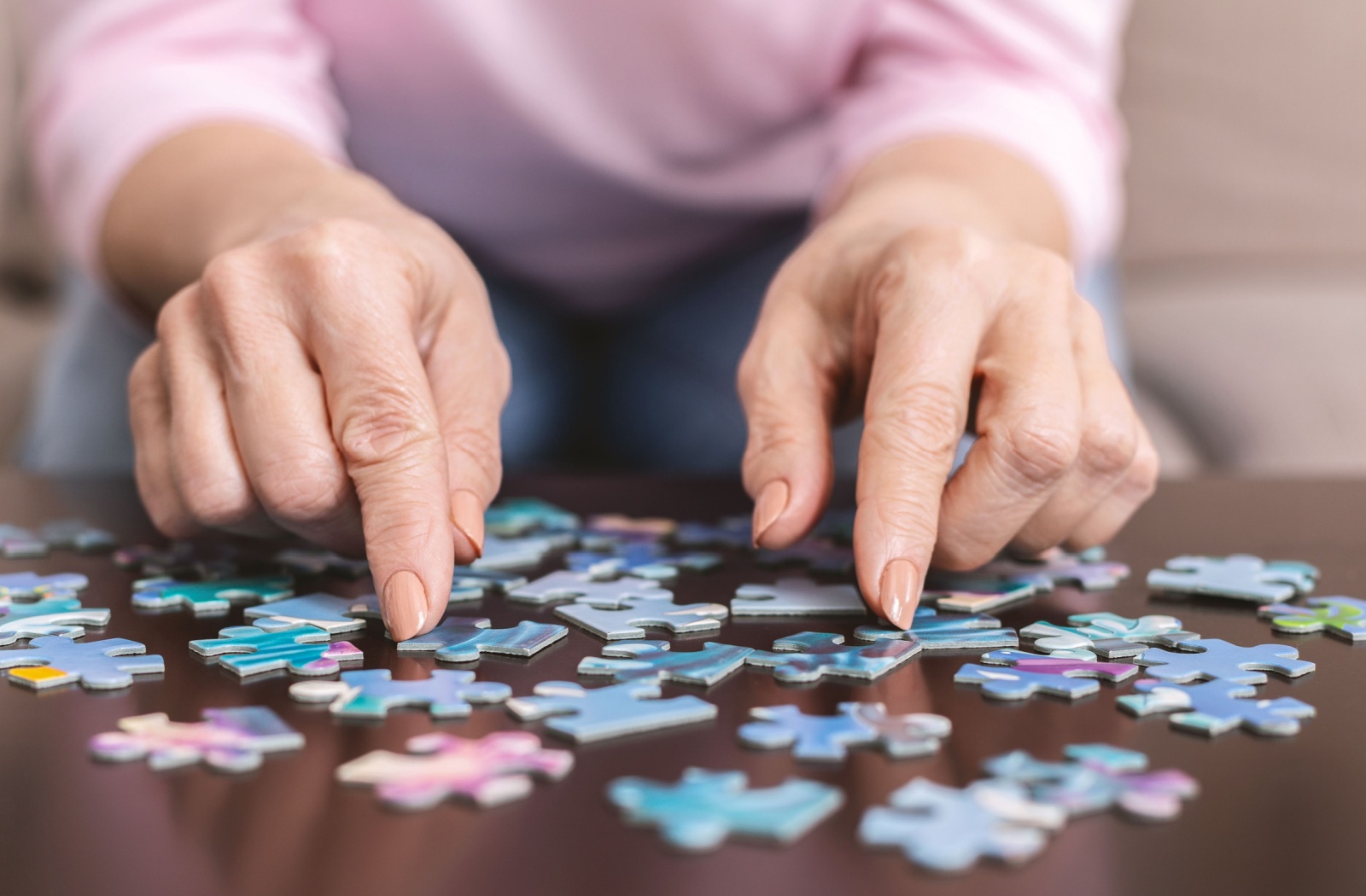 Close-up of a senior woman's hands doing a jigsaw puzzle.