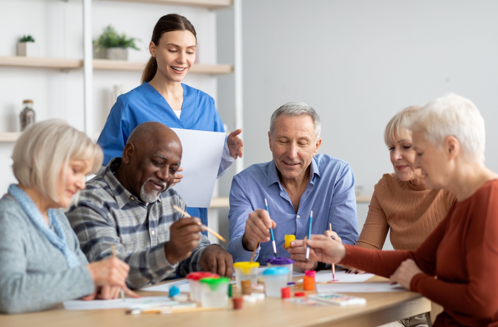 A caregiver takes a group of senior stroke survivors through a painting exercise.