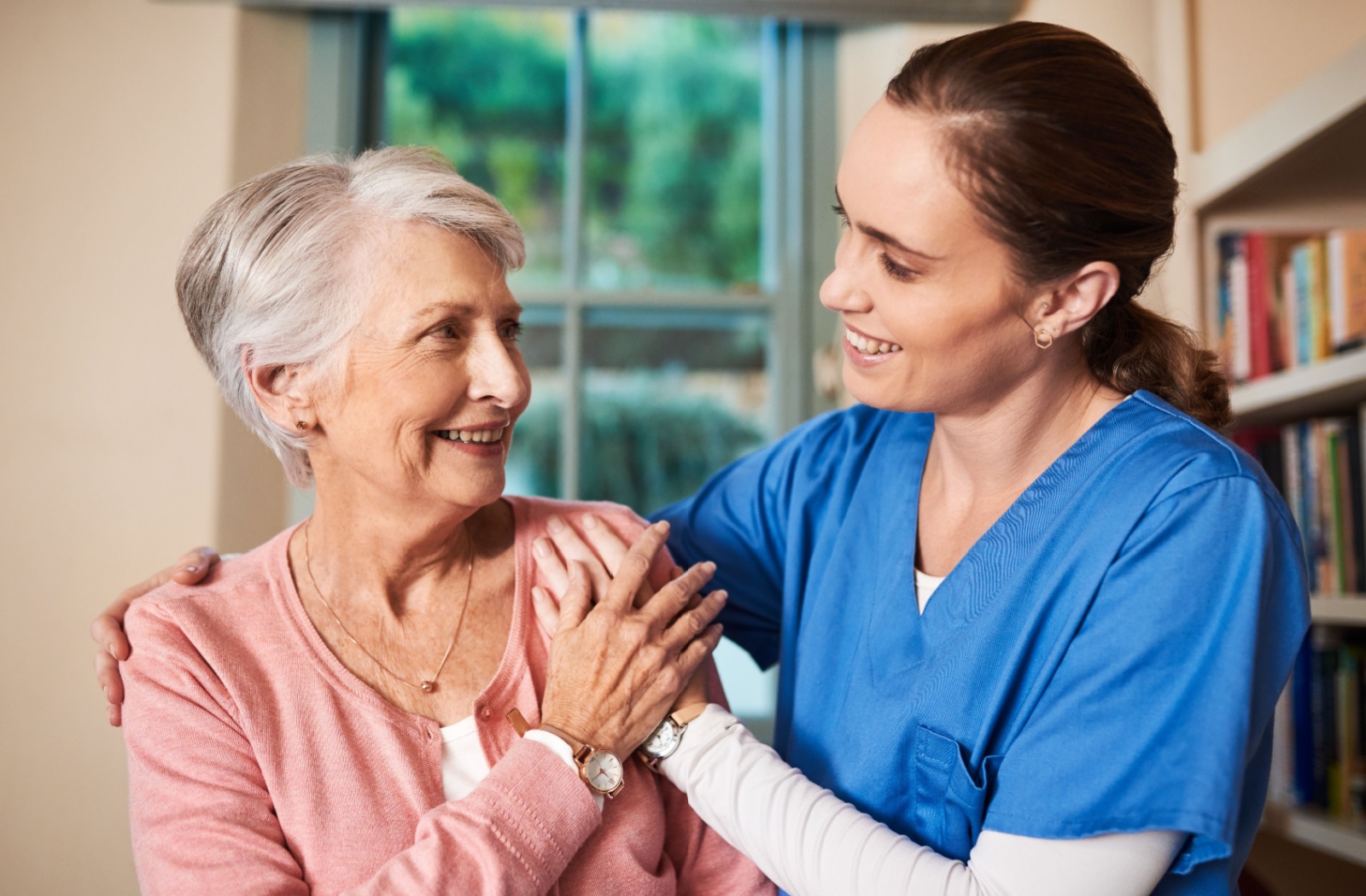 Respite caregiver providing emotional support to an older woman, smiling and comforting her with a gentle touch