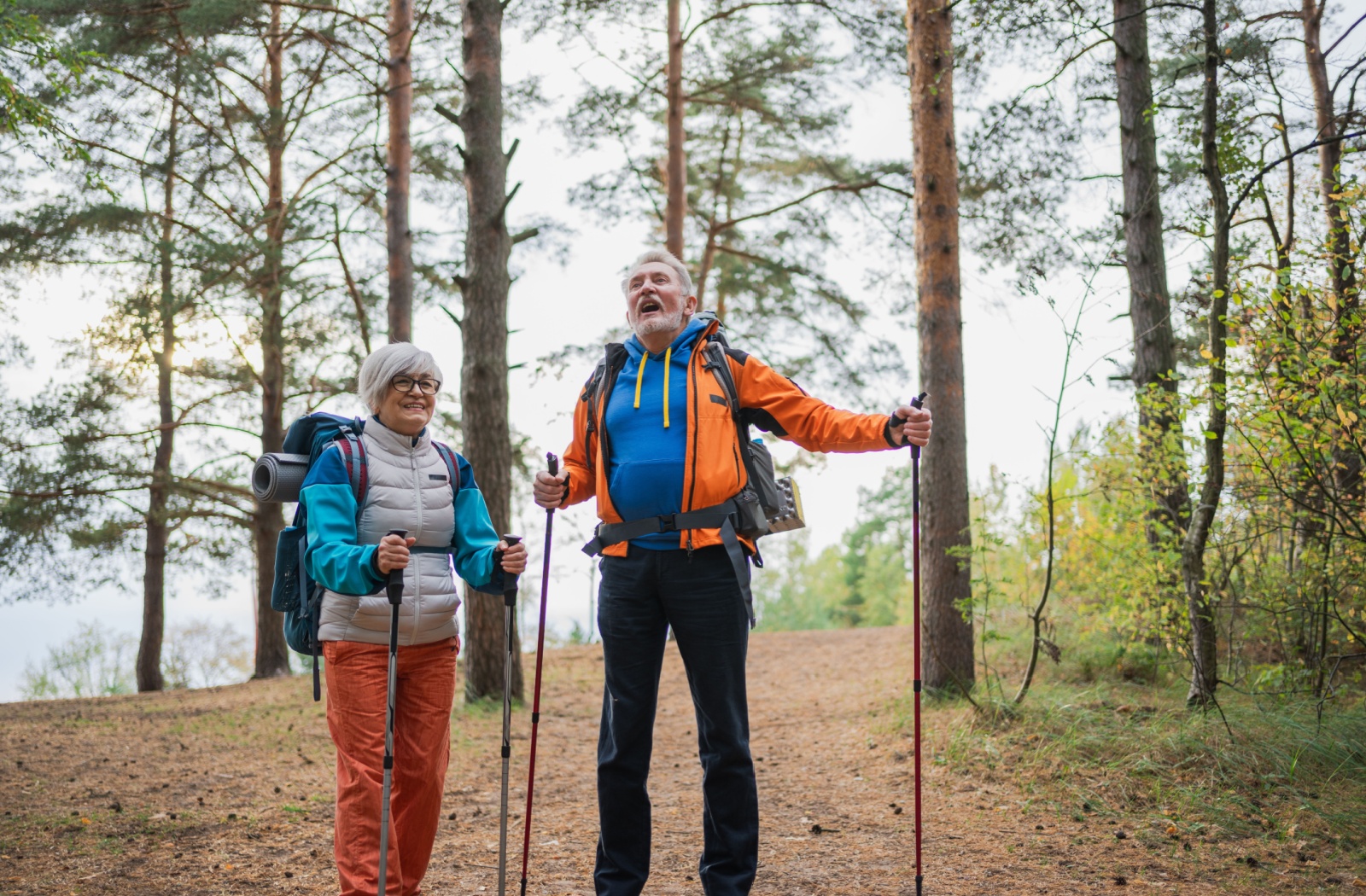 Two seniors hike on a small path to stay active.