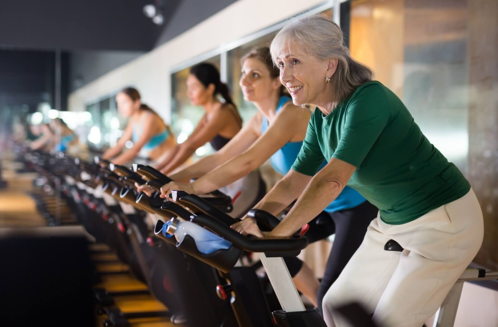 A senior with osteoporosis attends an indoor cycling class as a way to stay active and help strengthen their bones