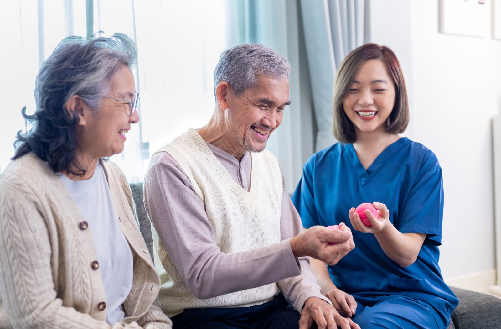 A senior living caregiver demonstrates hand exercises for a senior couple