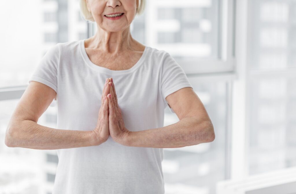 A senior in a white t shirt performing the prayer pose.
